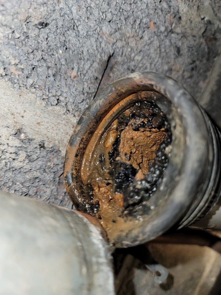 Clogged drain pipe before drain cleaning, coated inside with rust and black sludge