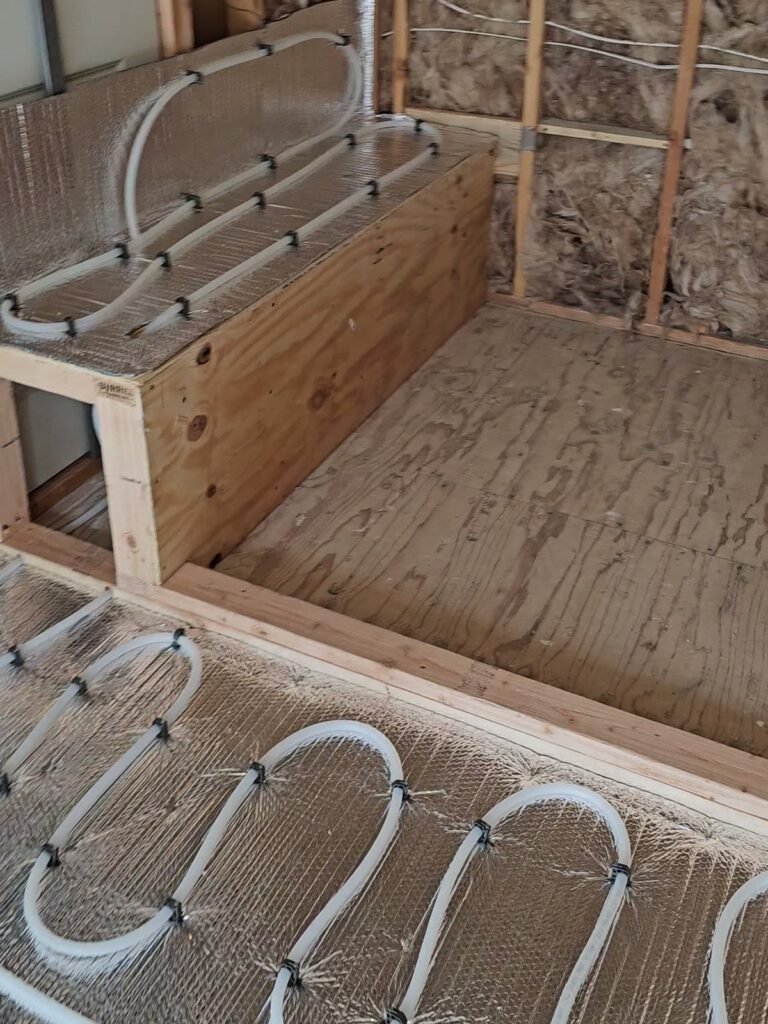 Radiant heating tubing on a bathroom floor and around a built-in bench installed by Absolute Precision
